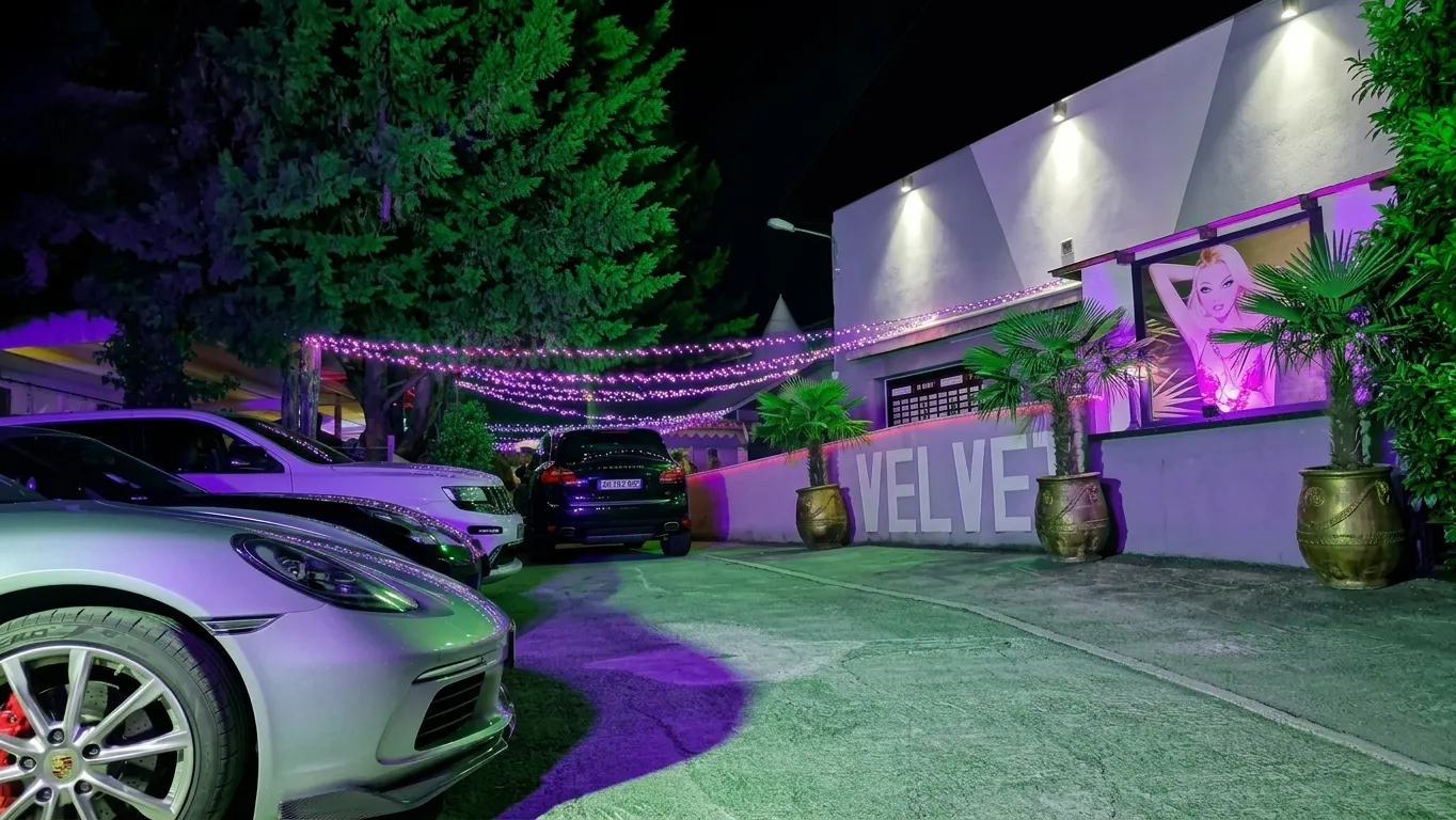 La façade du Velvet Club à Brignais la nuit, avec son enseigne Velvet, ses palmiers et son parking éclairé de violet