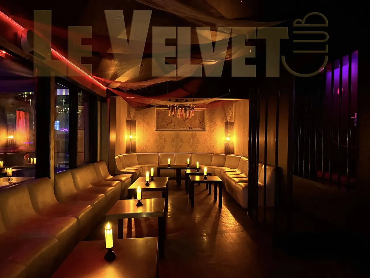 Un salon lounge du Velvet Club : banquettes crème, tables basses et bougies, sous une lumière tamisée